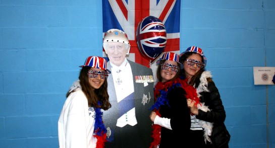 Students don red, white, and blue and pose with a King Charles life-size cut-out to celebrate the Coronation