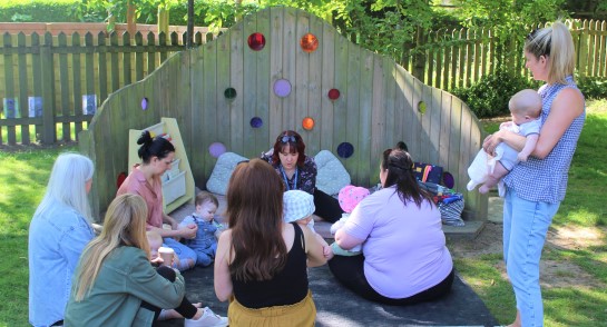 Parents and their children gather in the Highfield Pre-School garden for stories