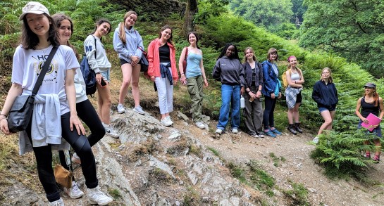 A group of pupils from Harrogate Ladies' College pose against on a hill in the Lake District, with greenery behind them