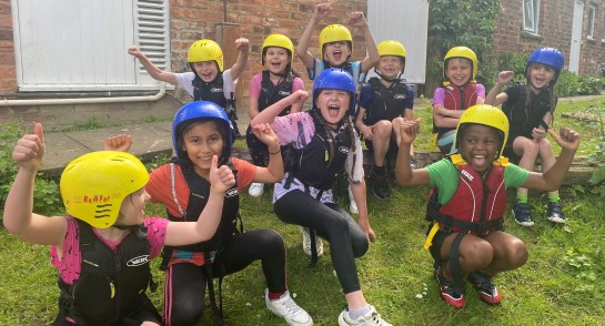 A group of joyful Prep 3 pupils from Highfield Prep School wearing safety jackets and colourful helmets