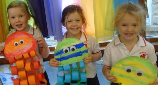 Three Highfield Prep School Reception children show colourful octopus artwork they have created
