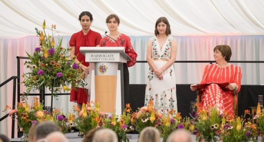 Three young women stand before a Harrogate Ladies' College podium to deliver speeches at HLC Speech Day